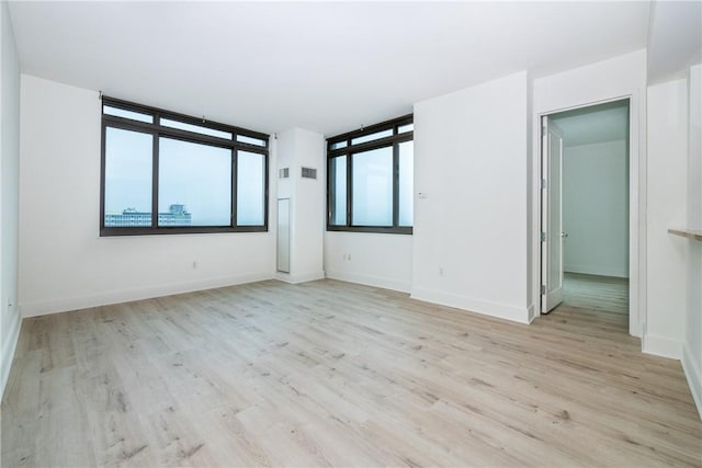 spare room featuring plenty of natural light and light hardwood / wood-style flooring