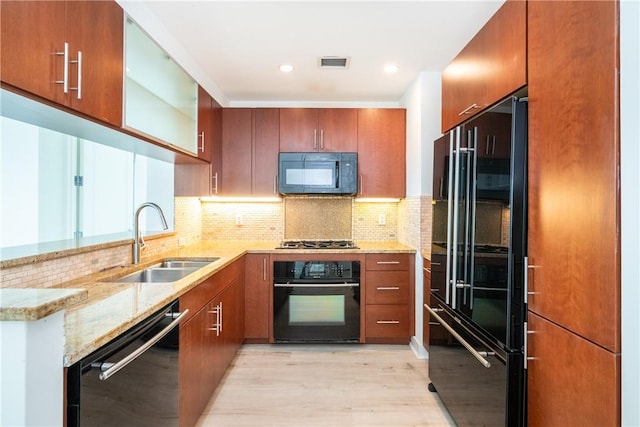 kitchen featuring black appliances, sink, light wood-type flooring, light stone counters, and kitchen peninsula