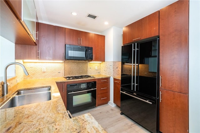 kitchen with sink, stainless steel gas cooktop, light stone counters, backsplash, and light hardwood / wood-style floors