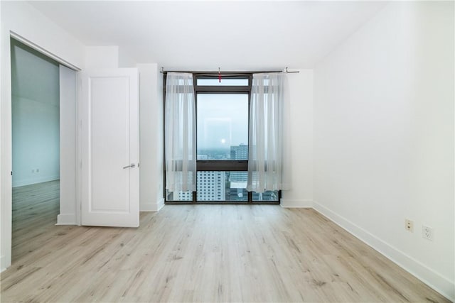 unfurnished room featuring expansive windows and light wood-type flooring