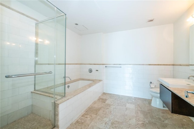 full bathroom with shower with separate bathtub, vanity, toilet, and tile walls