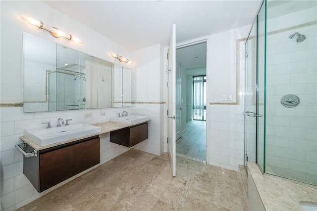 bathroom with vanity, a shower with shower door, and tile walls