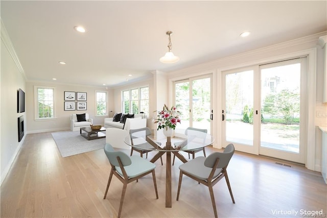 dining room with a healthy amount of sunlight, light wood-type flooring, and ornamental molding