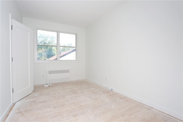 spare room featuring radiator and light hardwood / wood-style floors