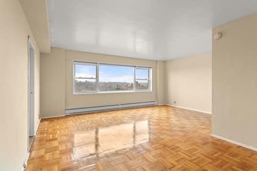 empty room with light parquet flooring and a baseboard heating unit