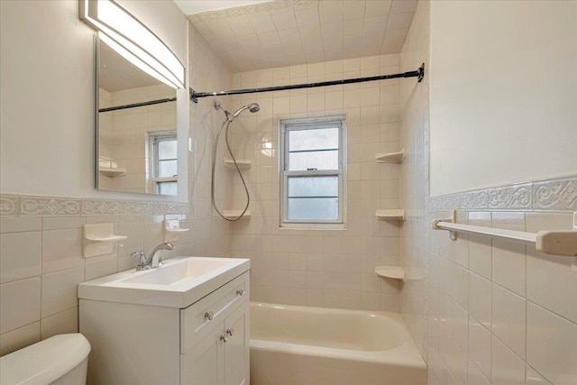 full bathroom with vanity, toilet, tile walls, and tiled shower / bath combo