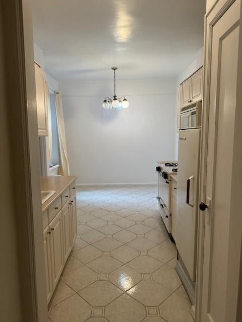 kitchen with pendant lighting, light tile patterned flooring, white appliances, and an inviting chandelier