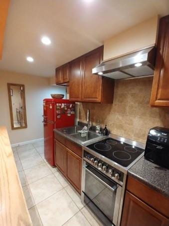 kitchen with decorative backsplash, light tile patterned floors, wall chimney range hood, and appliances with stainless steel finishes