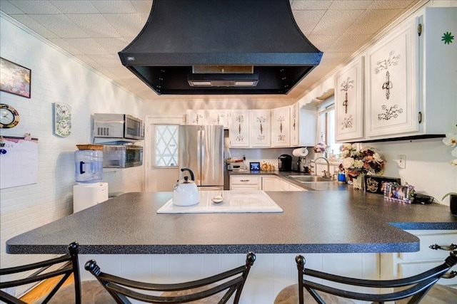 kitchen featuring appliances with stainless steel finishes, a kitchen breakfast bar, white cabinetry, and exhaust hood