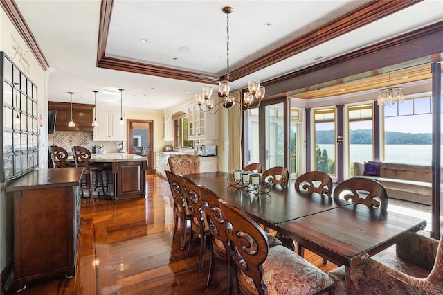33 Livingston Ave, Dobbs Ferry, NY 10522 - dining area with a chandelier, ornamental molding, dark wood-style flooring, a tray ceiling, and a water view
