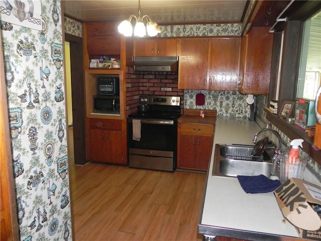 kitchen featuring black microwave, sink, hanging light fixtures, extractor fan, and electric stove