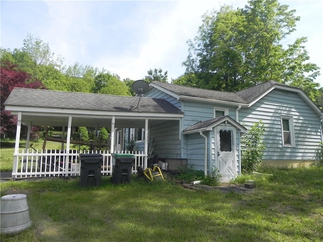 rear view of property featuring a porch and a yard