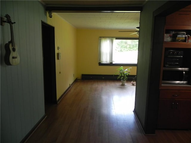 hallway featuring wooden walls, dark wood-type flooring, and a baseboard radiator