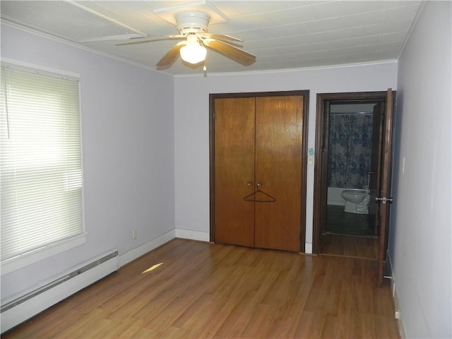 unfurnished bedroom featuring connected bathroom, ceiling fan, a baseboard radiator, crown molding, and wood-type flooring