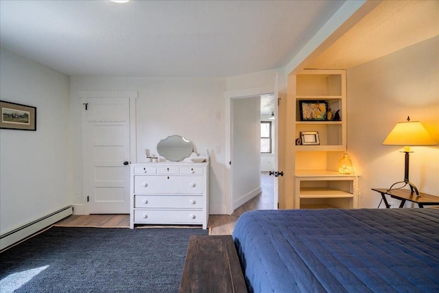 bedroom with light hardwood / wood-style floors and baseboard heating