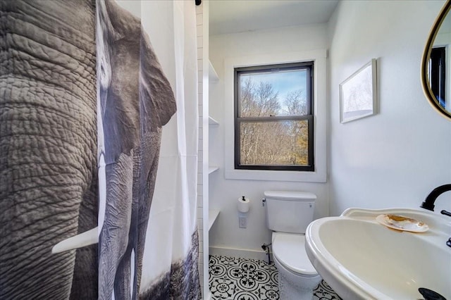 bathroom featuring tile patterned flooring, toilet, sink, and walk in shower