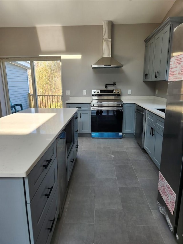 kitchen featuring gray cabinetry, wall chimney exhaust hood, and stainless steel appliances