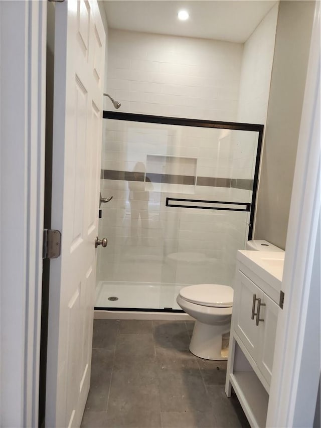 bathroom with vanity, toilet, and a shower with door