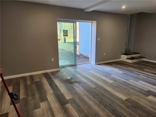 unfurnished living room with beamed ceiling and dark wood-type flooring