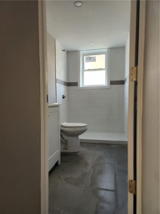 bathroom with tiled shower and toilet