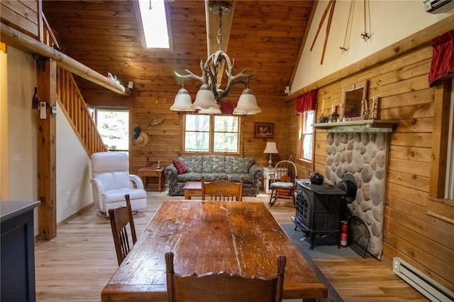 dining area featuring hardwood / wood-style floors, a wood stove, high vaulted ceiling, a baseboard heating unit, and a notable chandelier