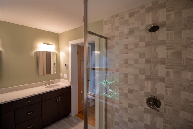 bathroom with vanity, a tile shower, and wood-type flooring