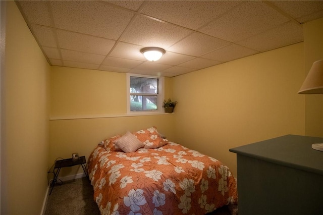 bedroom featuring a drop ceiling and dark carpet