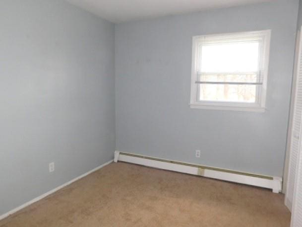 carpeted empty room featuring baseboard heating