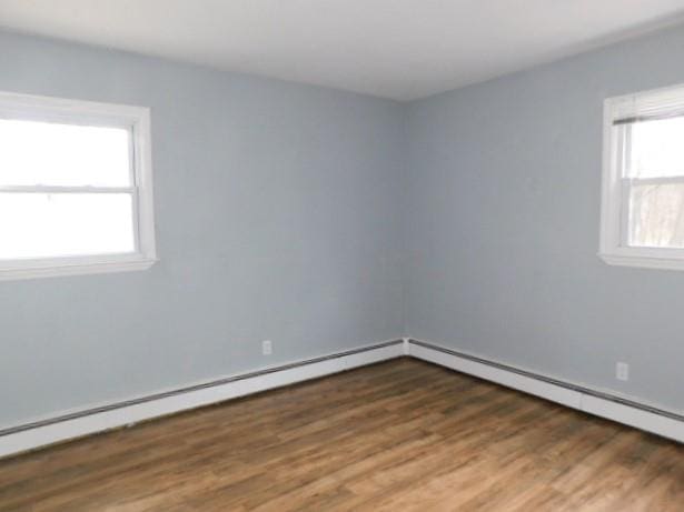 empty room featuring dark hardwood / wood-style flooring and a baseboard radiator