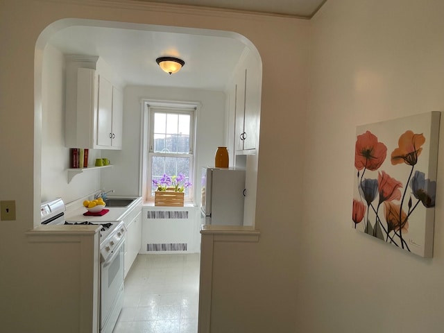 kitchen with white appliances, arched walkways, white cabinets, radiator heating unit, and a sink