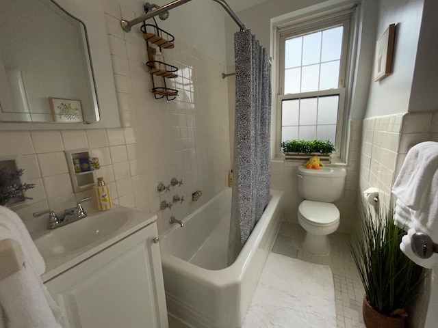 full bath with toilet, shower / tub combo, vanity, and tile walls