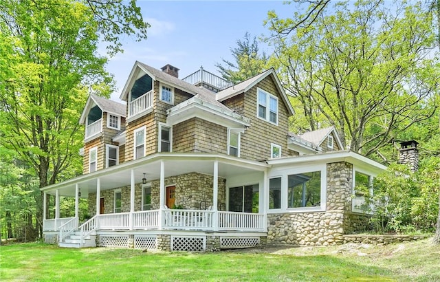 rear view of property featuring a porch and a yard