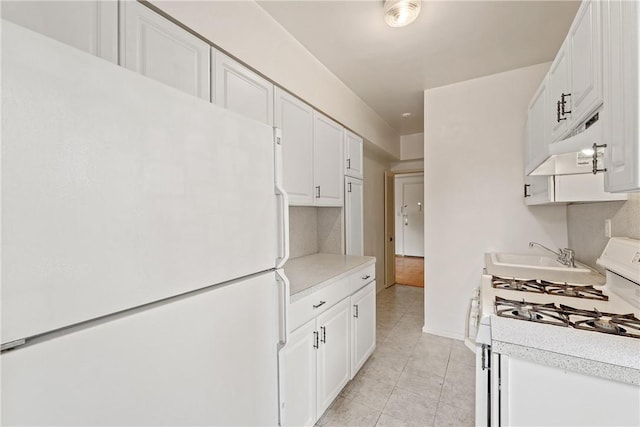 kitchen with white cabinets, light tile patterned floors, and white appliances