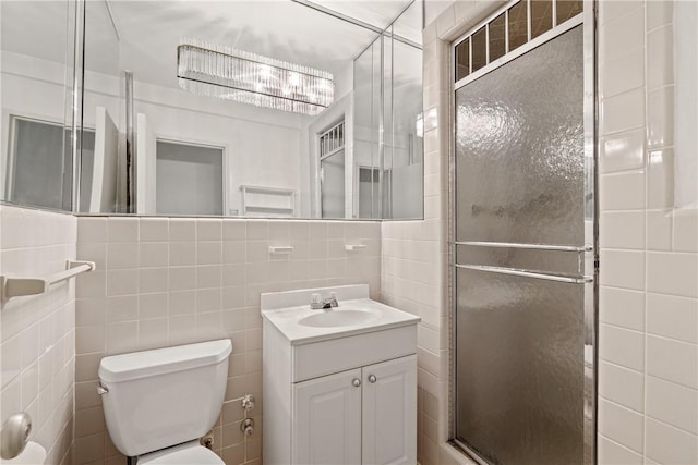 bathroom featuring vanity, toilet, tile walls, and a shower with shower door