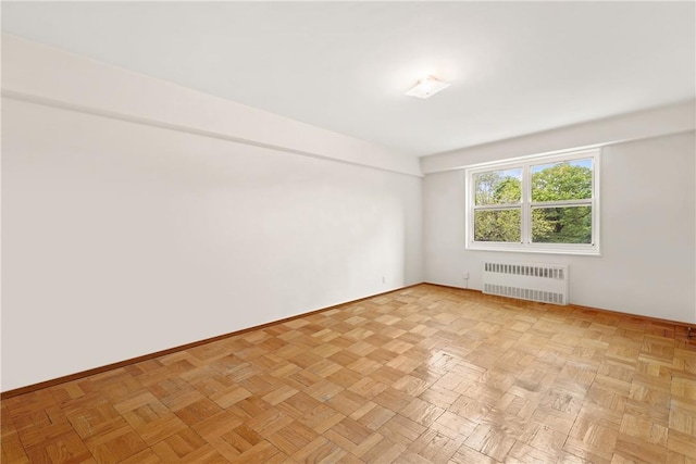 spare room with radiator and light parquet floors