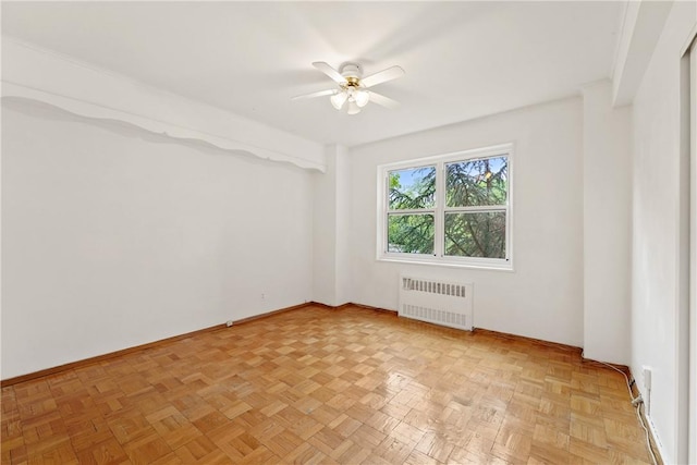 spare room with radiator, ceiling fan, and light parquet flooring