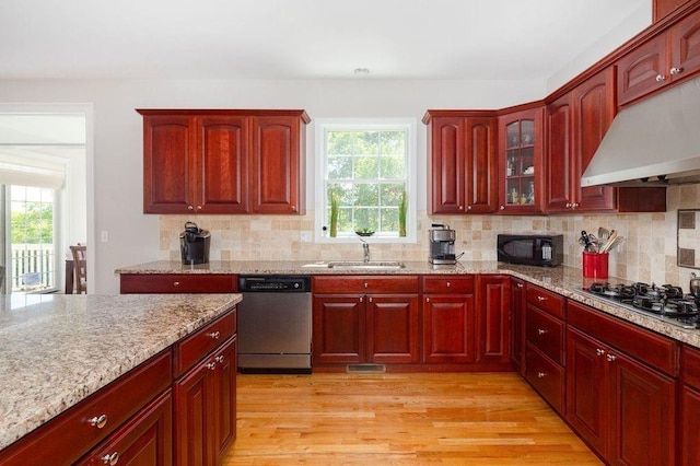 kitchen featuring ventilation hood, sink, decorative backsplash, light wood-type flooring, and stainless steel appliances