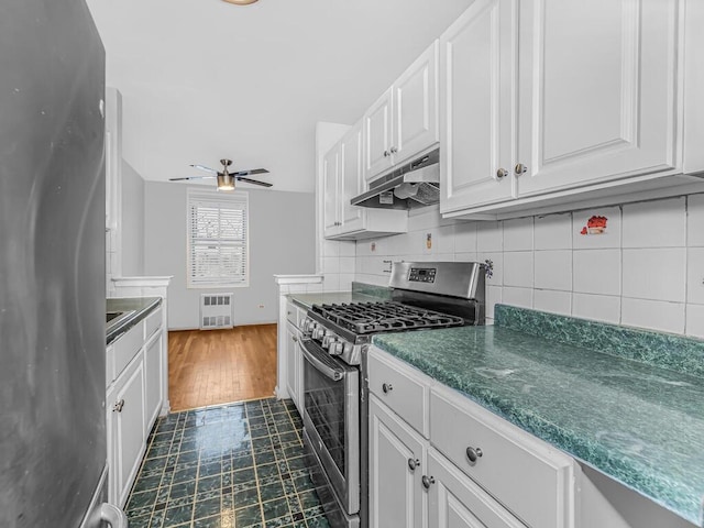 kitchen with decorative backsplash, heating unit, stainless steel appliances, ceiling fan, and white cabinetry