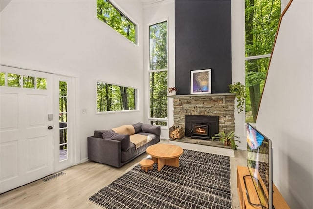 interior space with a wood stove, a towering ceiling, and light wood-type flooring