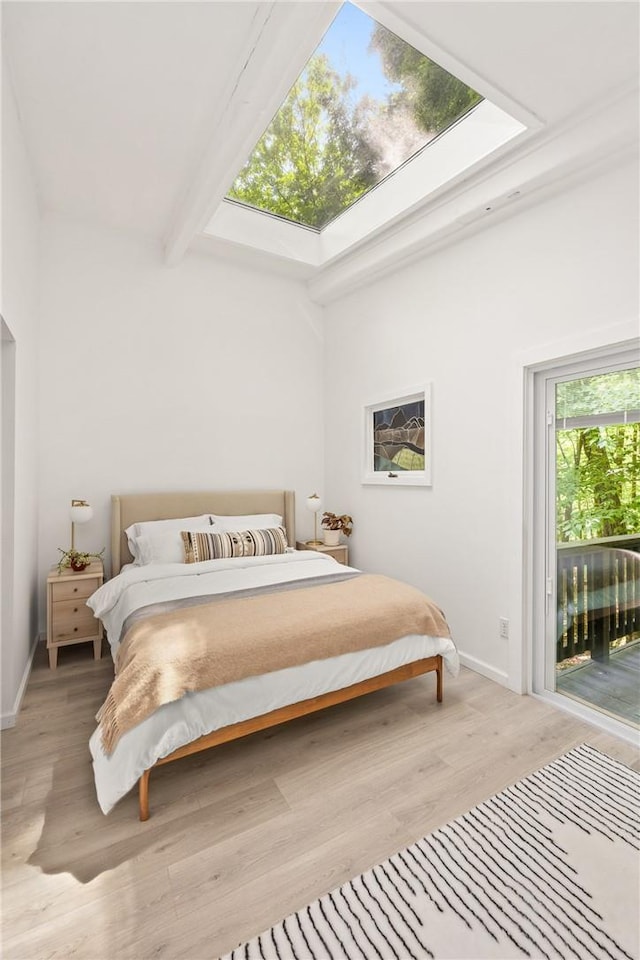 bedroom with access to exterior, a high ceiling, and light wood-type flooring