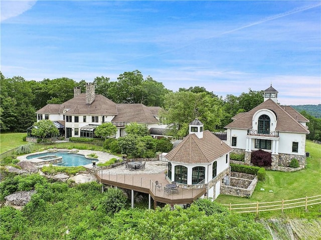 rear view of property with a lawn and a fenced in pool