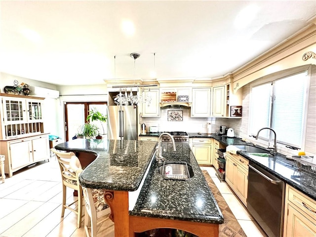kitchen featuring sink, an island with sink, appliances with stainless steel finishes, and dark stone counters