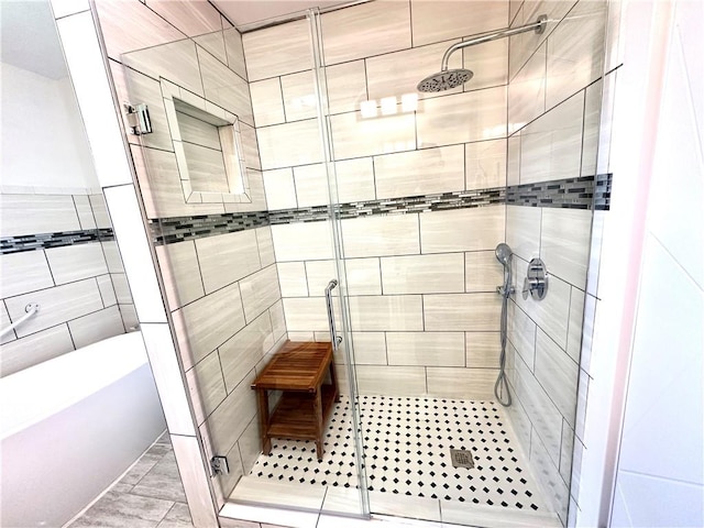 bathroom with shower with separate bathtub and tile walls