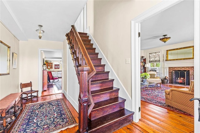 stairway featuring hardwood / wood-style flooring and a brick fireplace