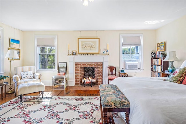 bedroom featuring multiple windows, hardwood / wood-style floors, cooling unit, and a fireplace