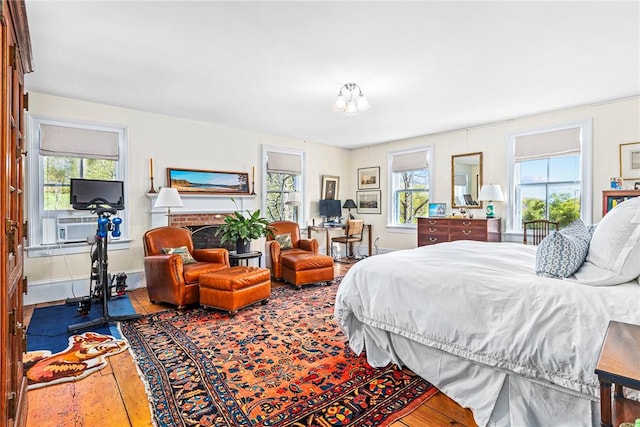 bedroom featuring a fireplace, hardwood / wood-style floors, and multiple windows