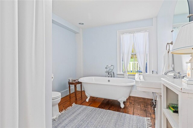 bathroom featuring hardwood / wood-style flooring, a bathtub, toilet, and sink