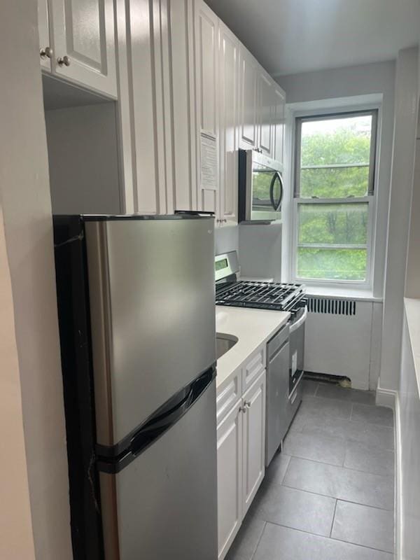 kitchen with light tile patterned floors, white cabinetry, and appliances with stainless steel finishes