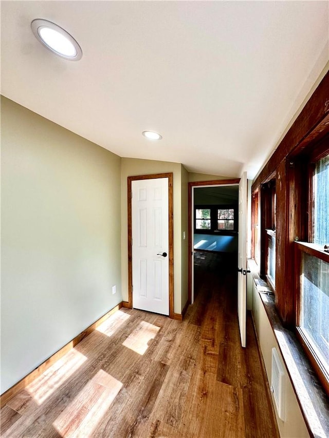 hallway featuring vaulted ceiling and hardwood / wood-style flooring