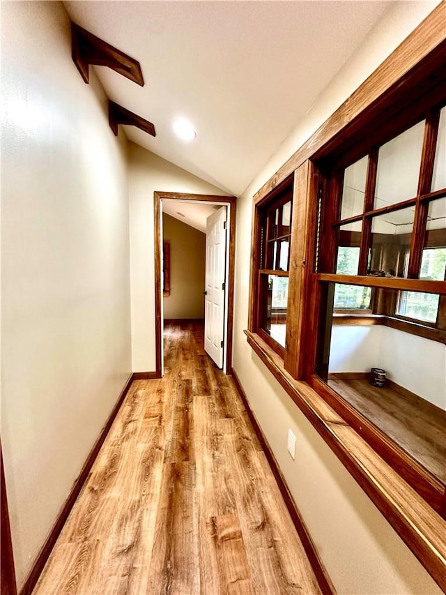 corridor with lofted ceiling and light wood-type flooring